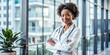 © kansak01 - African American female doctor stands confidently in her office, arms crossed, stethoscope around her neck, exuding professionalism, expertise, and pride in her medical service.