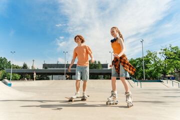 Two teenagers with roller skates and skateboard riding at the skate park