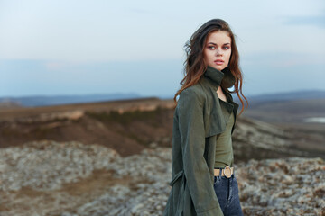 Wall Mural - Woman in green jacket enjoys scenic mountain view from hilltop