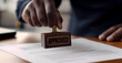 © Mel - Close up of an male hand stamping a document with the word 'APPROVED', lawyer