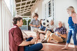 © Marko Geber - Multigenerational family playing soccer on house porch