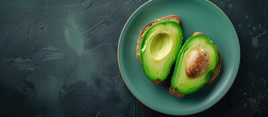 Poster - Top view of two avocado toast slices on a dark background displayed on a turquoise plate providing copy space image
