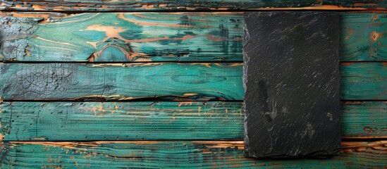Poster - A view from above showing a black stone cutting board placed on a green wooden tabletop with space for writing or images. Creative banner. Copyspace image