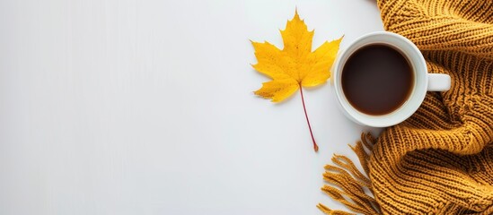 a fall themed setup with a cup of coffee cozy sweater and a yellow maple leaf on a white backdrop pr