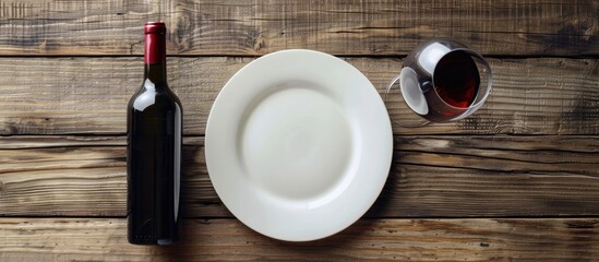 Canvas Print - A top down view of a table arrangement showing an empty plate wine glass and a red wine bottle on a rustic wooden table background with copy space image