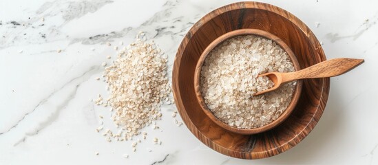Poster - Copy space image of a wooden bowl with a spoon filled with psyllium husk resting on a white marble table