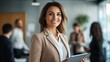 © tang - Businesswoman leader holding a tablet in her hand and standing in an office at team meeting.