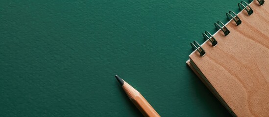 Fototapete - Wooden pencil placed on a green background near a notebook with ample copy space image
