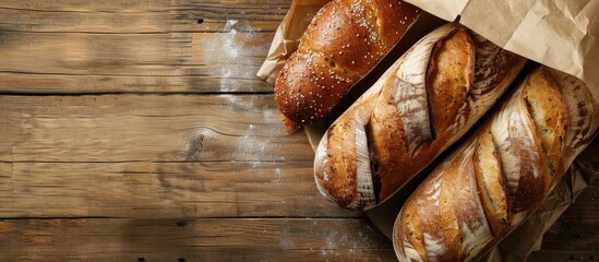Poster - Fresh bread loaves displayed on a wooden background with a paper bag in a top view copy space image