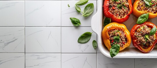 Wall Mural - A white tiled table displays a baking dish filled with quinoa stuffed bell peppers and basil from a top view leaving room for a text on the copy space image