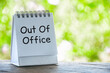 © JeromeMaurice - Out Of Office text on white notepad with bright green nature background. Vacation or holiday concept