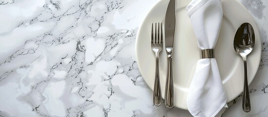 Poster - Top view of a chic dining arrangement with silverware and napkin on a white marble table alongside a designated copy space image