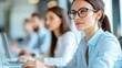 © JK_kyoto - Focused woman with glasses working on laptop in a modern office environment. A scene of concentration and teamwork.