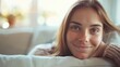 © iuricazac - Smiling young woman in casual attire resting on a stylish sofa, surrounded by a bright and modern home setting.