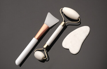 Wall Mural - White jade roller and gua sha scraper, spatula for cream on black background