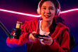 © Summit Art Creations - Host channel of beautiful Asian girl streamer with joystick playing online game wearing headphones pastel color talking with viewers media online. Esport skilled team players in neon room. Stratagem.
