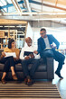 © SensSai/peopleimages.com - Business people, speaking and relax on couch in office with ceo for monthly meeting, project updates or conversation. Boss, graphic designer team and communication for creative brief and feedback.