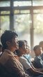 © MikeLegend - Attentive audience in a classroom setting with sunlight streaming through windows.