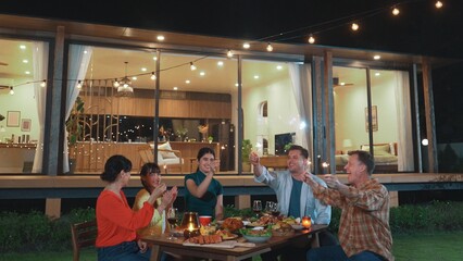 Happy family holding glowed sparkler in holiday celebration party at night. Lovely member enjoy playing spark toy together. Outdoor activity to cross generation gap strengthen family bond. Divergence.