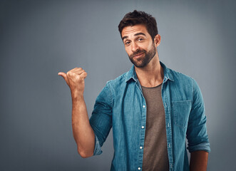 Poster - Happy man, portrait and pointing with deal, notification or alert on a gray studio background. Male person or handsome model showing selection, advertising or sale in choice, sign up or mockup space