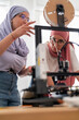 © Studio Marmellata - Two women in hijabs collaborate on setting up a 3D printer, carefully adjusting and calibrating the machine. Their teamwork emphasizes precision and technical skills in engineering.
