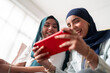 © Studio Marmellata - Two women in hijabs smile as they play a game on a tablet. Their expressions show joy and engagement, highlighting a fun and relaxed atmosphere with modern technology.