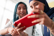 © Studio Marmellata - Two women in hijabs smile as they play a game on a tablet. Their expressions show joy and engagement, highlighting a fun and relaxed atmosphere with modern technology.