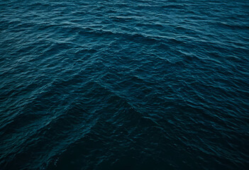 Blue green surface of the ocean with gentle ripples and light refracting. aerial view of tropical sea on a dark and cloudy day.