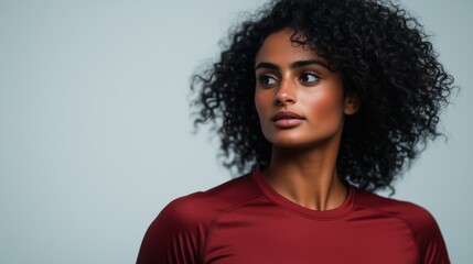 Portrait of a young African American female athlete in a red sports jersey, gazing confidently into the distance against a light gray background