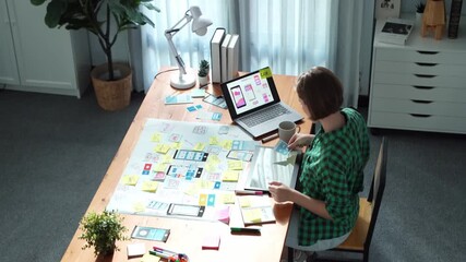 Top view of manager design UX, UI system while sitting at table and looking at tablet with program system display. Leader writing idea by using sticky note and mind map to brainstorm idea.Convocation.