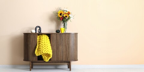 Poster - Wooden cabinet with bouquet of autumn flowers and plaid near beige wall. Banner for design