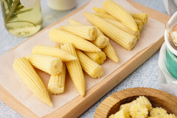 Wall Mural - Wooden board with tasty canned corn cobs on light background