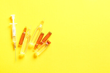 Wall Mural - Ampules, bottle with medicines and syringe on yellow background