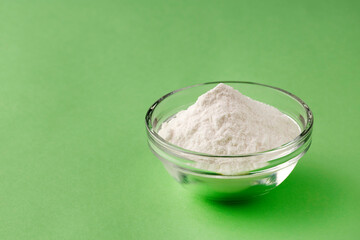 Baking soda powder in the bowl - Healthy food. Green background