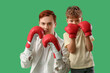 © Pixel-Shot - Little boy with his father in boxing gloves on green background