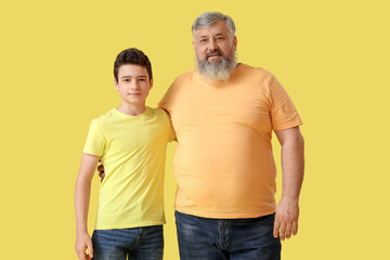 Wall Mural - Happy grandfather with his cute grandson on yellow background