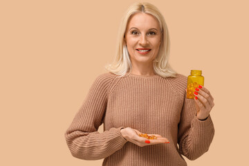 Wall Mural - Mature woman with fish oil pills on beige background