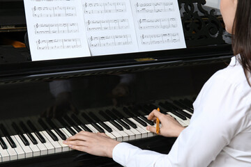 Poster - Young woman playing piano with note sheet