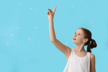 Poster - Cute girl with soap bubbles on blue background