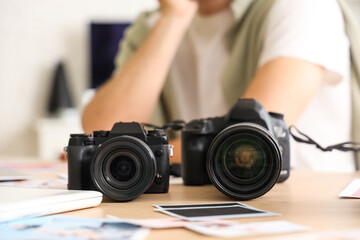 Canvas Print - Professional male photographer with modern cameras sitting in studio