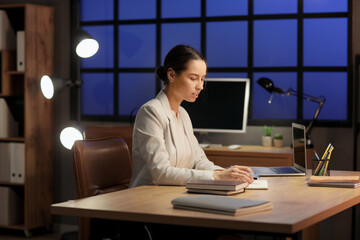 Wall Mural - Young woman writing in notebook at workplace in office