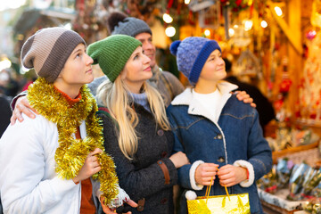 Portrait of positive family of four choosing christmas balls at Xmas street fair