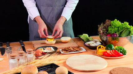 Young Chef layering sliced vegetables and boiled egg on bread bun with fresh ingredients on kitchen counter