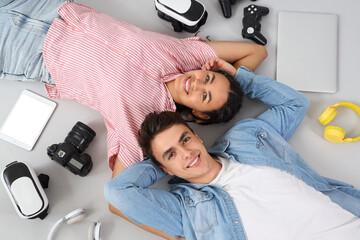 Poster - Young couple with modern gadgets lying on light background, top view