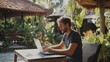 © The Little Hut - Young digital nomad working remotely on his laptop in Bali Freelancer Man in workation video call Travel and remote online work Outdoor in the garden desk for  remote workers someone a : Generative AI