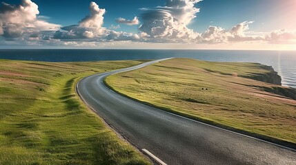 An empty road in a green pasture by the ocean 