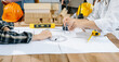 © Nuttapong punna - Creative architect projecting on the big drawings with architectural project at construction site