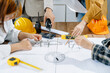 © Nuttapong punna - Engineer teams meeting working together wear worker helmets hardhat on construction site