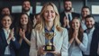© Oulaphone - Business success concept. Happy winner businesswoman receives a business award and holding trophy with team of cheerful workers. Celebrating and congratulating their leader on great work success.