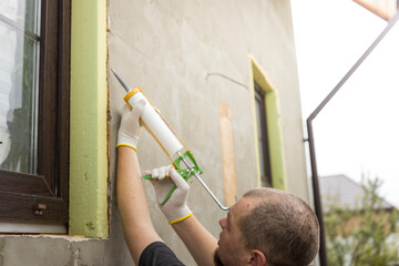 Wall Mural - A man is painting a wall with a spray gun